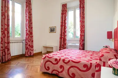 a bedroom with a red bed and two windows at Domus Lilium in Rome