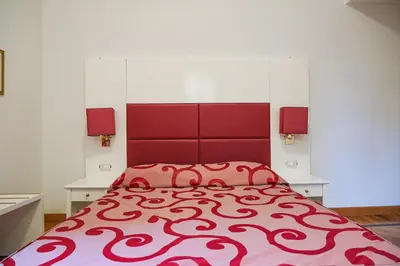 a bedroom with a large red bed with two tables at Domus Lilium in Rome