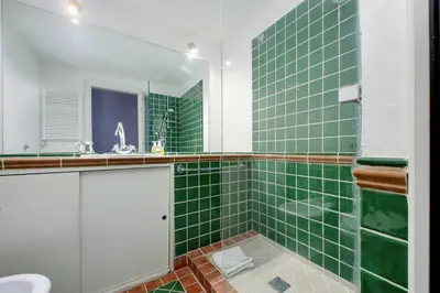 a green tiled bathroom with a sink and a mirror at Beautiful Apartment in Campo de Fiori in Rome
