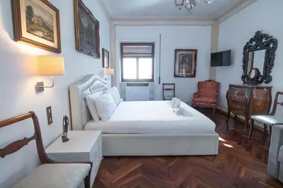 a bedroom with a white bed and a chair at The Majestic Residence in Vatican in Rome