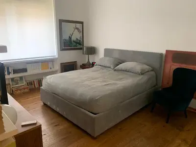 a bedroom with a large bed and a chair at Appartamento con terrazza centrale e luminoso in Rome