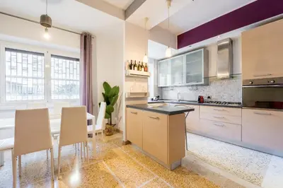 a kitchen with white cabinets and a table and chairs at Luigi's Home, Cozy Apartment Metro San Paolo in Rome