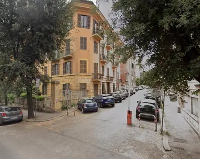 a street with cars parked in front of a building at La Dimora Torlonia Elegance & light in Rome in Rome