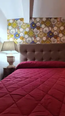 a bedroom with a bed with a red comforter and a wall at Hybris Campo De' Fiori in Rome