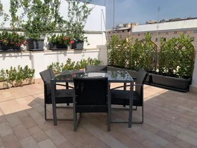 a glass table and chairs on a patio at Tristar Terrace Penthouse in Rome
