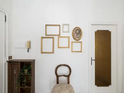 a room with a white wall with pictures on the wall at Blessy apartment Vaticano in Rome
