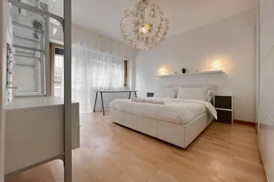 a white bedroom with a bed and a chandelier at La Casa di Roma in Rome