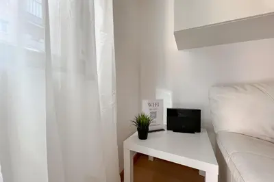 a white room with a white bed and a white table with a tv at La Casa di Roma in Rome
