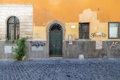a building with a green door and some graffiti at Milo Apt - Trastevere's Gem in Rome