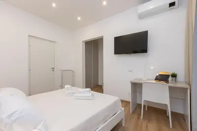 a white bedroom with a desk and a bed at Colosseum Holidays - Three-Bedroom Apartment in Rome