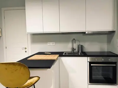 a kitchen with white cabinets and a sink and a chair at Vatican Tiny House in Rome