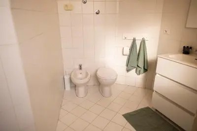 a white bathroom with a toilet and a sink at Porto Fluviale Penthouse - Rome Collection in Rome