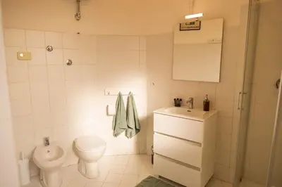 a white bathroom with a toilet and a sink at Porto Fluviale Penthouse - Rome Collection in Rome