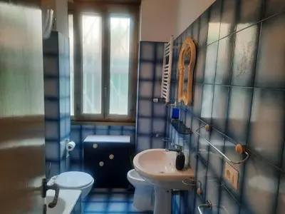 a blue tiled bathroom with a sink and a toilet at Nido Vidaschi in Rome