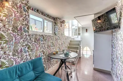 a living room with a table and a wall with floral wallpaper at Terrazza Ippocrate in Rome