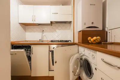 a kitchen with white cabinets and a washer and dryer at Carla Luxury House in Rome