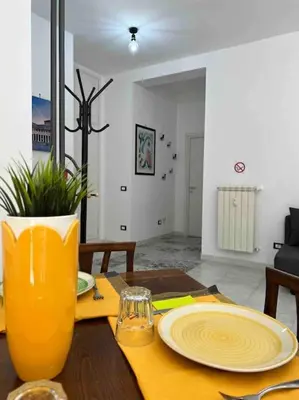 a table with a yellow vase and plates on it at 3 FERMATE DAL COLOSSEO - Casa Vacanze Elena - 50 m da METRO GARBATELLA in Rome