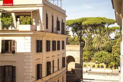 a white building with a balcony and trees in the background at GuestHost - La finestra sui palazzi di Roma Apartment in Rome