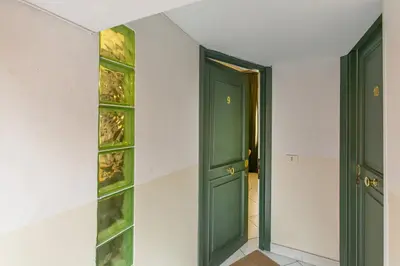 a hallway with green doors and glass shelves at Trevi Little Palace #9 in Rome