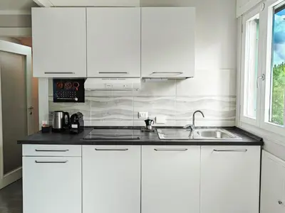 a white kitchen with a sink and white cabinets at Rome Essence Apartament in Rome
