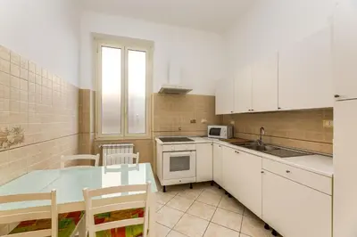 a kitchen with white cabinets and a table with chairs at Magenta Tiburtino in Rome