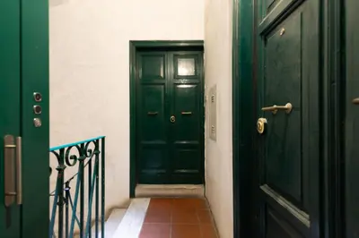 a green door in a hallway next to a staircase at Trevi Apartment in Rome