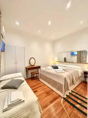 a bedroom with two beds and a table and a mirror at Vacanze Romane Laterano in Rome