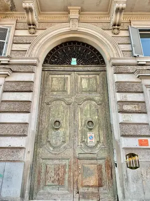 a large wooden door in a building with an arch at Vacanze Romane Laterano in Rome