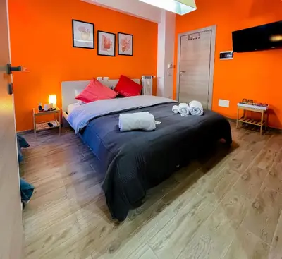 a bedroom with a large bed with orange walls at LE TRIPLETTE in Rome