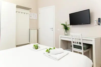 a white bedroom with a desk and a tv on the wall at B&B Casetta Roma in Rome