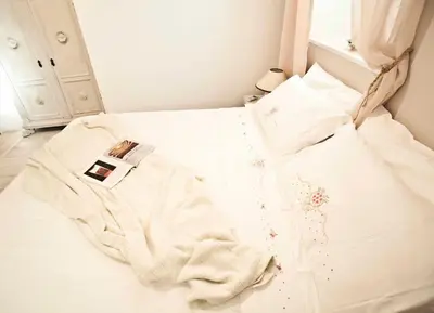 a bed with white sheets and a watch on it at SottosopraSannio in Rome