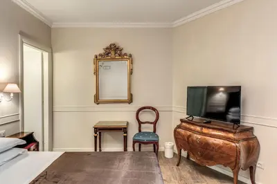 a bedroom with a tv and a chair and a mirror at Aurelius Ponte Sant'Angelo in Rome