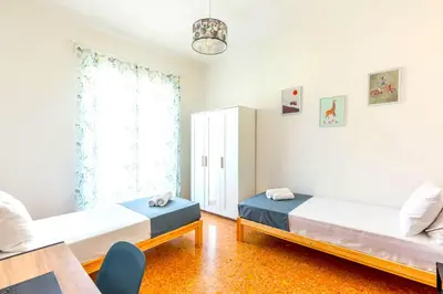 a bedroom with two beds and a window at Hostly - Family Home Stresa in Rome