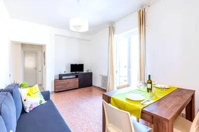 a living room with a table and a blue couch at Hostly - Family Home Stresa in Rome