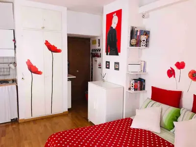 a room with a bed with red sheets and red flowers at Lovely studio near the Colosseum in Rome
