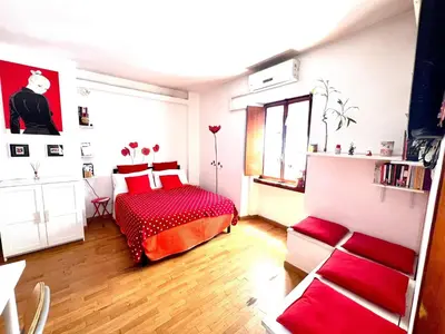a bedroom with a red bed and a window at Lovely studio near the Colosseum in Rome
