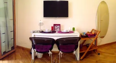 a table with two chairs and a tv on the wall at L'Appartamento Romano in Rome