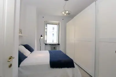 a white bedroom with a bed and a window at Cattaneo Flat in Rome