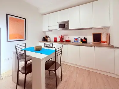 a kitchen with white cabinets and a table and chairs at Pandora apartments in Rome