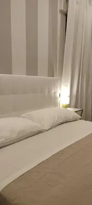 a white bed with a white headboard and a lamp at Portonaccio suite - Stazione Tiburtina - Università - Metro B in Rome