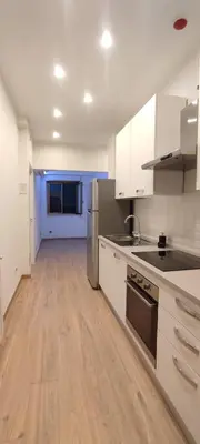 a kitchen with white cabinets and a wooden floor at Portonaccio suite - Stazione Tiburtina - Università - Metro B in Rome