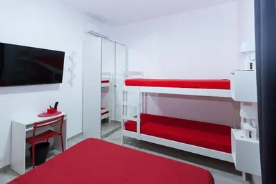 a bedroom with red and white bunk beds and a desk at Easy Apartment in Rome