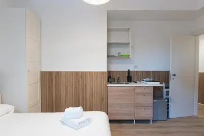a bedroom with a white bed and a kitchen at Residence San Paolo in Rome