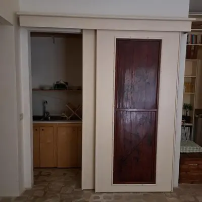 a wooden door in a room with a kitchen at HOUSE UP TO THE HILL - stanza con soggiorno a Monteverde vecchio in Rome