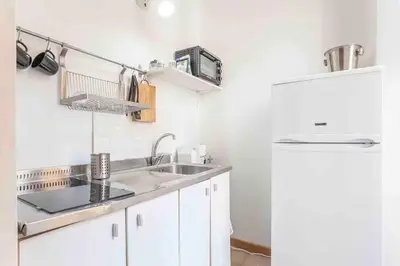 a white kitchen with a sink and a refrigerator at L’oasi di Trastevere in Rome