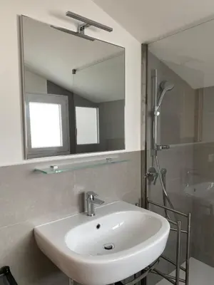 a bathroom with a sink and a shower with a mirror at Piccolomini Design Apartment in Rome