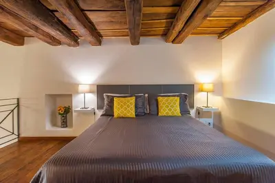 a bedroom with a large bed with two yellow pillows at L'antico borgo di Trastevere II in Rome