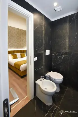 a bathroom with a toilet and a sink and a bed at Alba Rosa Rooms in Rome