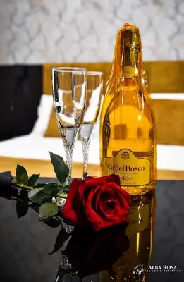 a bottle of wine and a rose next to two glasses at Alba Rosa Rooms in Rome