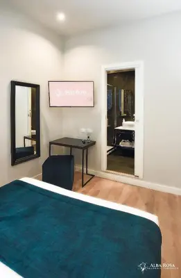 a bedroom with a bed and a table and a mirror at Alba Rosa Rooms in Rome